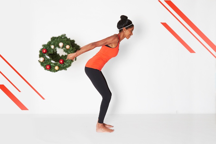 festive classes woman in sportwear exercising with two christmas wreaths