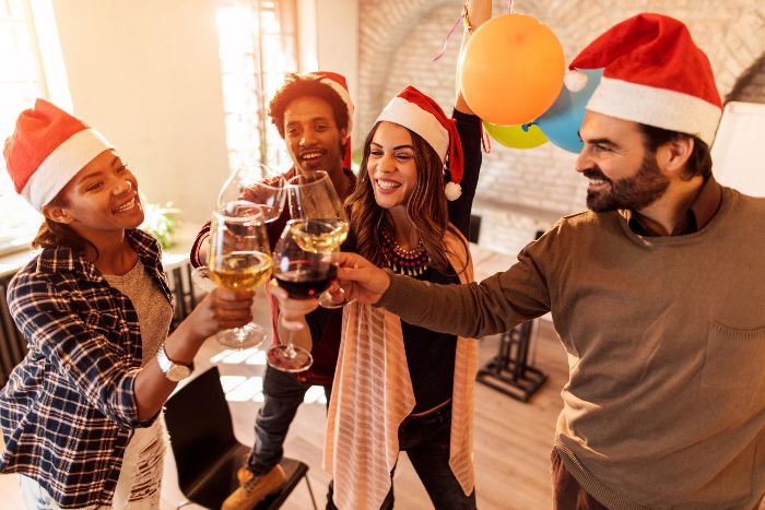 friends with santa hats raising a toast with whine glasses