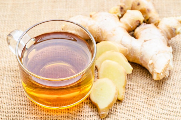 ginger tea in a glass cup with ginger root next to it on a cloth