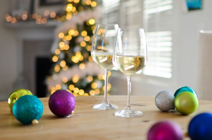 holiday glasses with white wine on a table with Christmas baubles