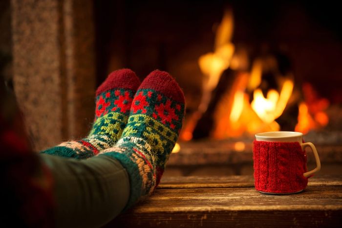 holiday relaxation feet in colorful socks in front of the fire with a mug dressed in red