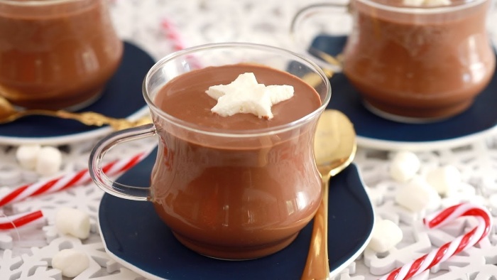 hot chocolate served in glass cups on dark plates with golden spoons 