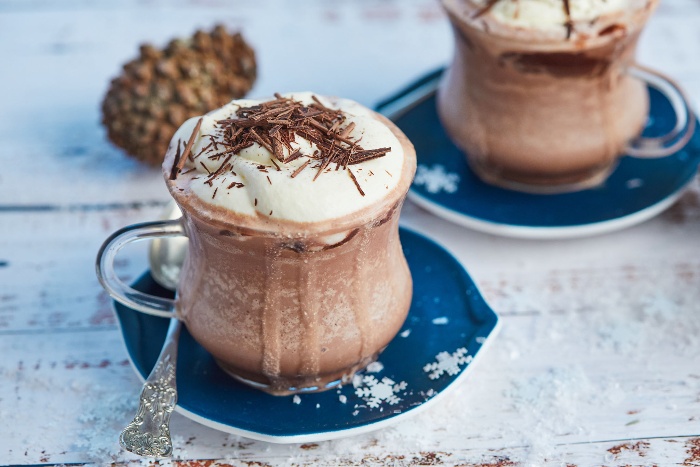 delicious hot chocolate in a glass cup on a blue plate sprinkled with chocolate