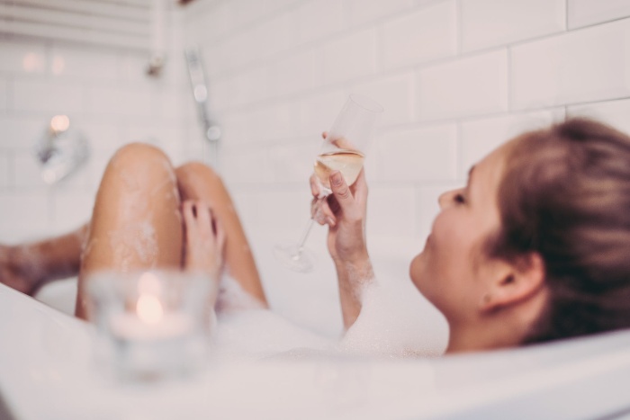 woman enjoying new year's eve in a bath with champagne glass in her hand 