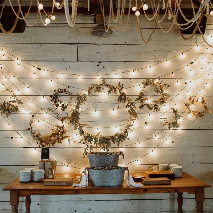 wall decor garlands of fairy lights and wreathes on a white wall above a table