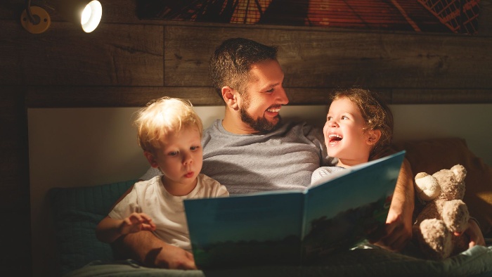 dad with two kids in bed reading a story from a book