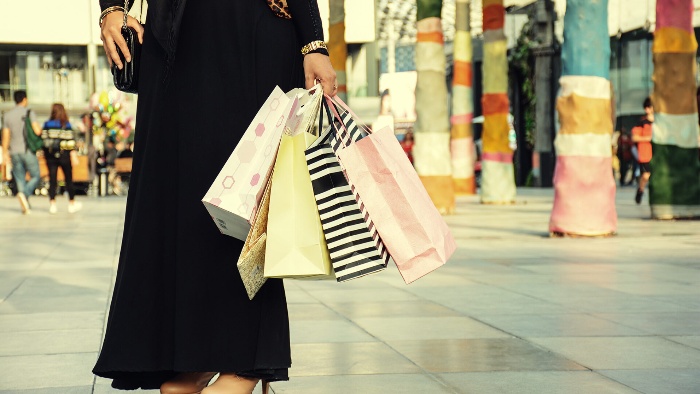 shopping in saudi arabia woman in a black burka holding colorful paper bags with gifts