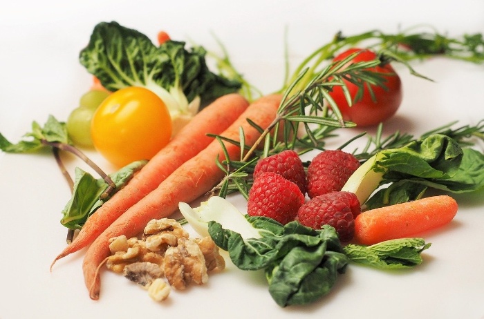 vegetables on a table carrot strawberries greens rosemary walnuts tomatos