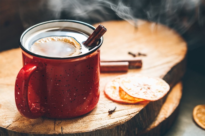 Hot tea with citrus slices and cinnamon sticks on a natural wooden surface