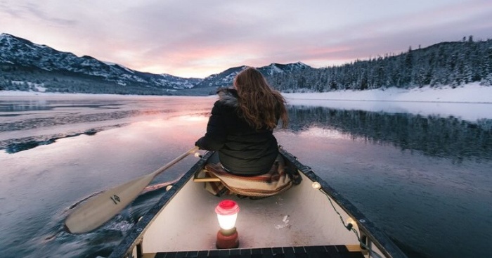 woman in a boat rowing among a snowy landscape