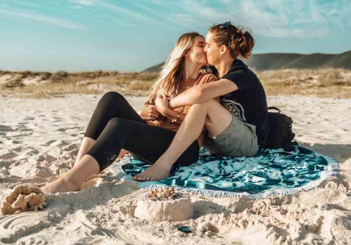 beach date couple cuddling and kissing on the beach