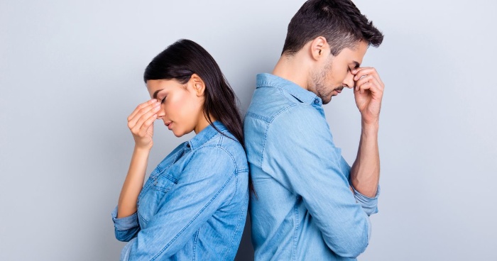 woman and man in denim shirt holding their heads back to back 