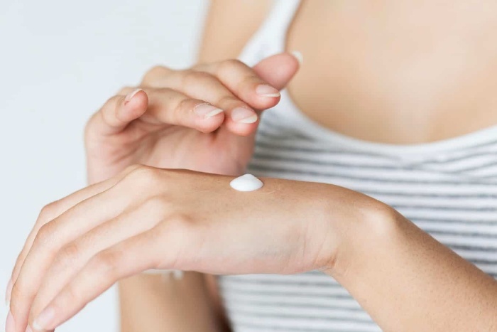 woman in a striped top with a drop of cream on her hand