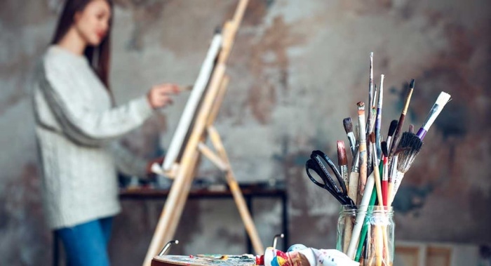 woman painting in an atelier with brushes and paint