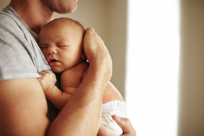 dad cuddling a small naked baby 