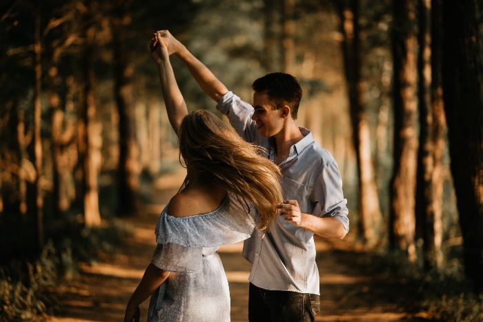 a girl and boy in love dancing in a forest