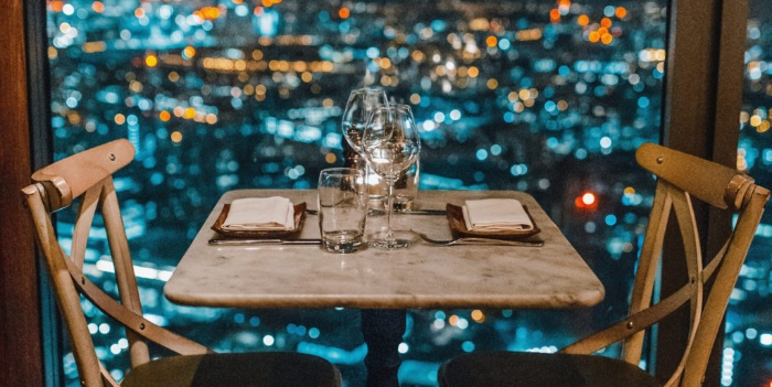 romantic date dinner table with two empty chairs in a restaurant with a view