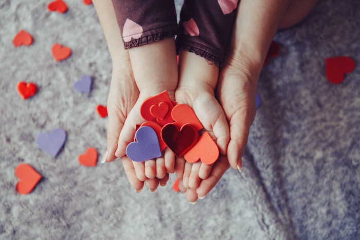 mother and child hands holding colorful paper hearts