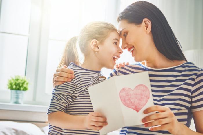 enjoying valentines day with kids mom and daughter holding a paper card with a heart