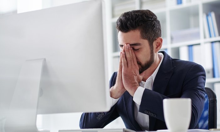 men entrepreneur in a black suit holding his face in front of a white monitor