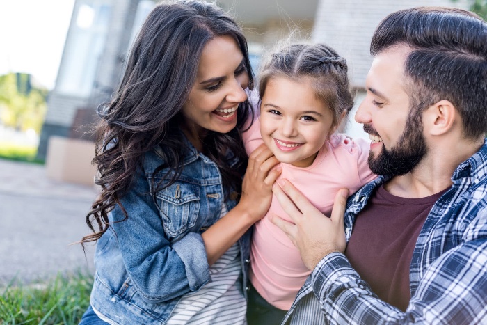 family fun mom dad and daughter cuddling outside having fun