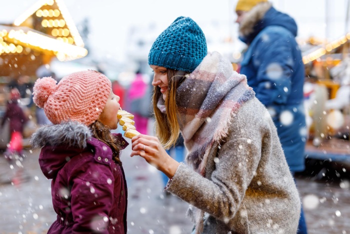 woman and daughter outside on a snowy day eating fruit