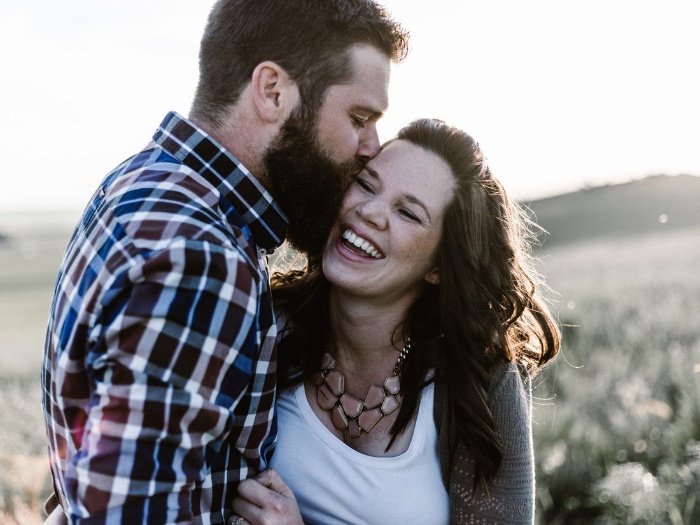 man in a shirt kissing a smiling woman outdoor photo