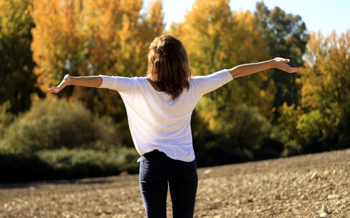 new year lessons woman with white shirt and jeans outdoors with her arms spread