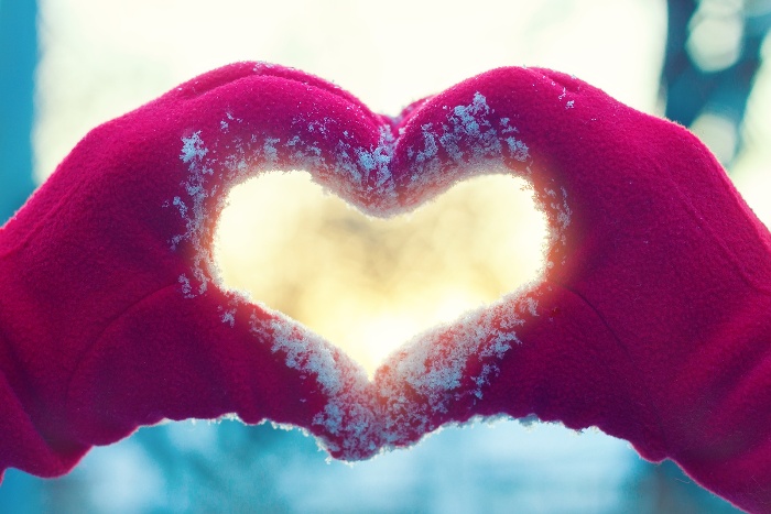 two hands in red gloves forming a heart in a snowy day