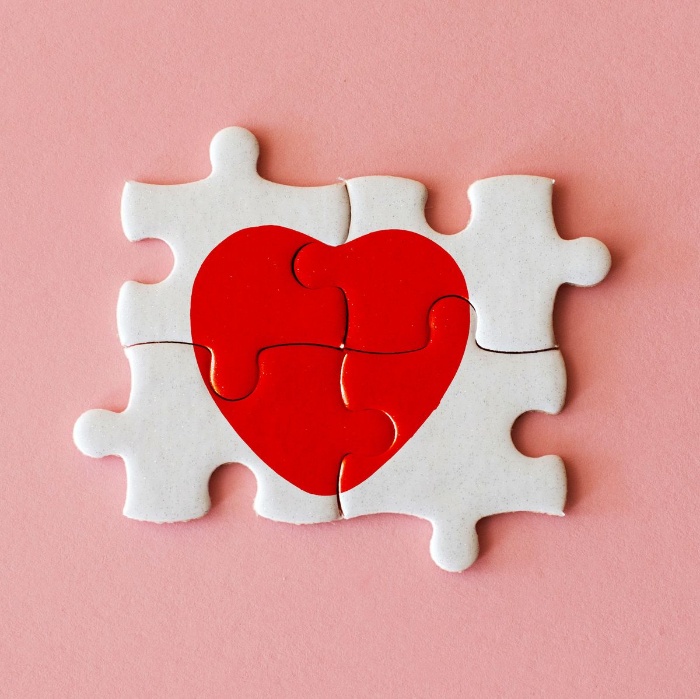 red heart on a white puzzle on a pink background