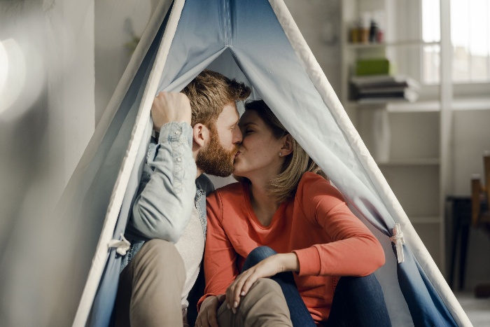 indoor camping couple kissing in a light blue tent at home