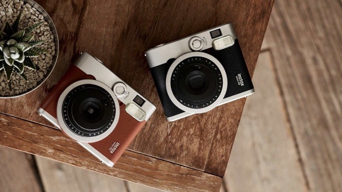 two instant cameras black and brown one lying on a table