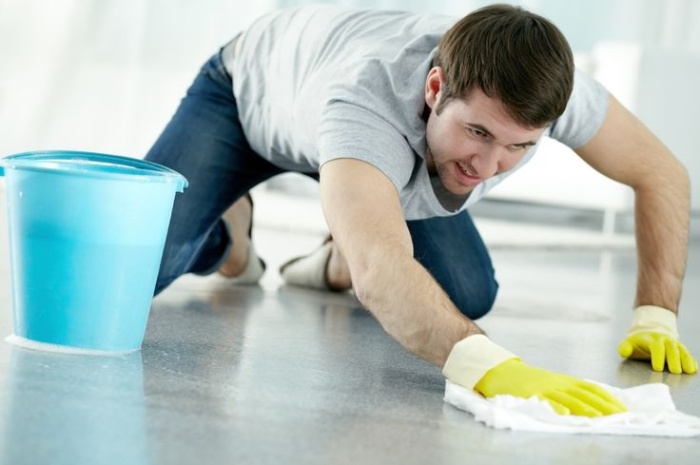 man in jeans, shirt and gloves cleaning the floor