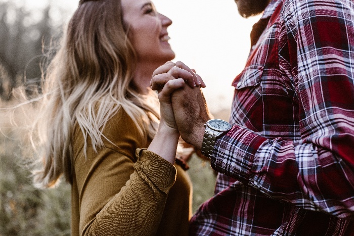 a couple holding hands and looking at each other smiling