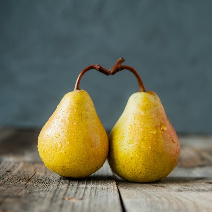 winter fruits two pears forming a hear on a wooden table and dark background