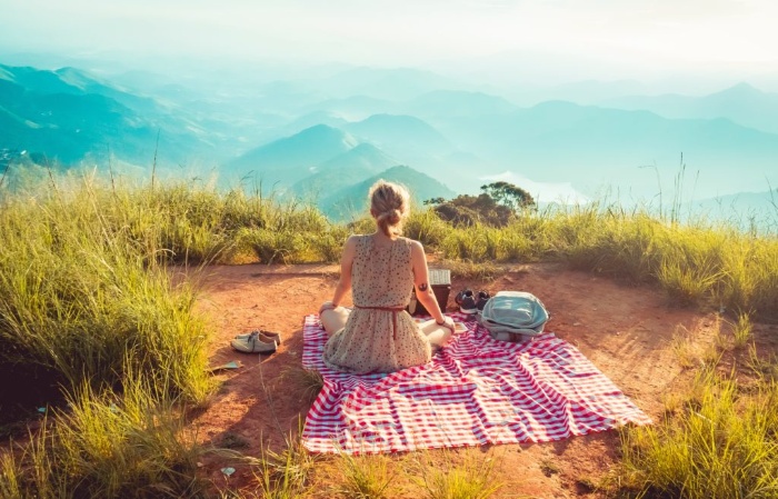 woman on a picnic alone in Nature watching a mountainous landscape 