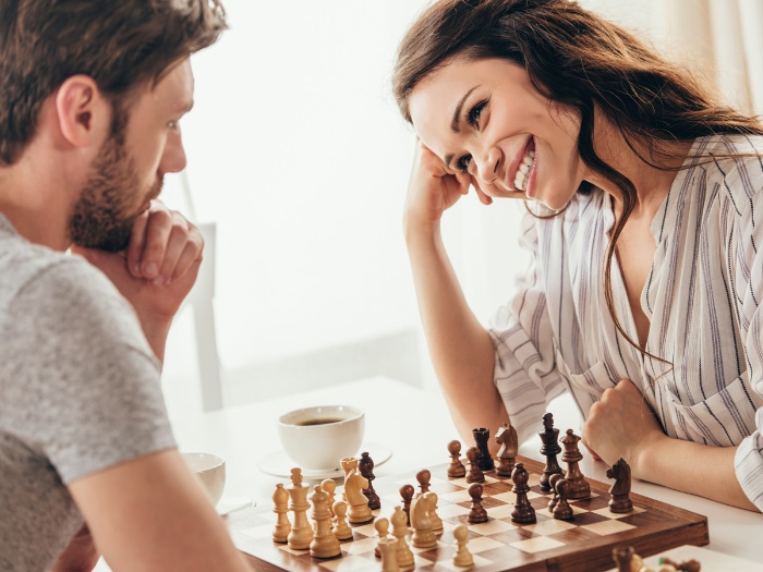 couple playing chess together woman watching a man smiling