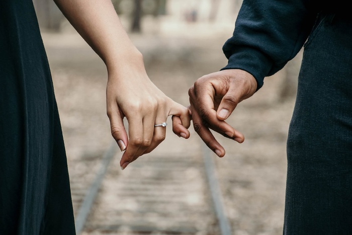 couple in dark clothes holding hands walking outside