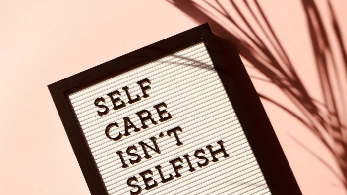 note in a black frame self care isn't selfish on a pink background