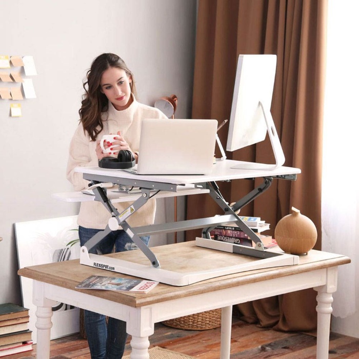 standing desk woman in her home office holding a mug with computers