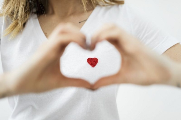 types of love woman in a white shirt making a heart sign with her hands 