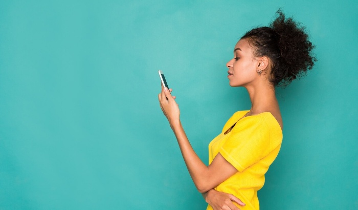 virtual dating woman in yellow shirt on a blue background watching her phone