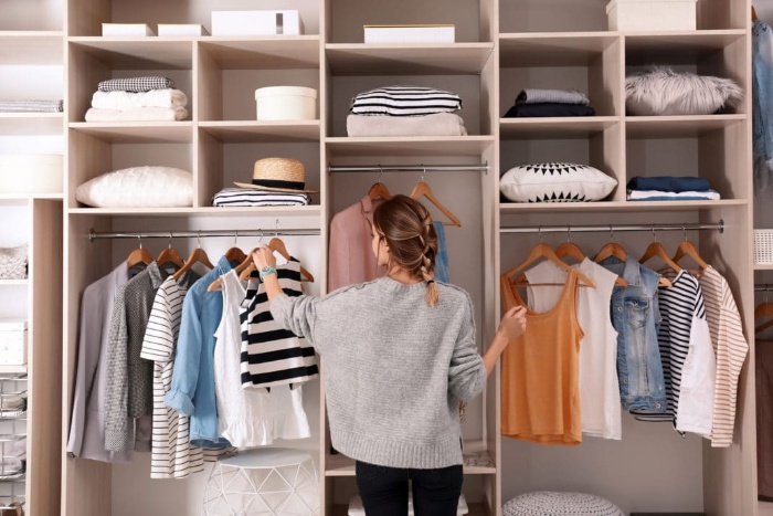 woman organizing her clothes in front of a large wardrobe 