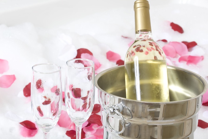 love and romance bubbly and chocolate champagne bottle in a cooler with glasses and rose petals