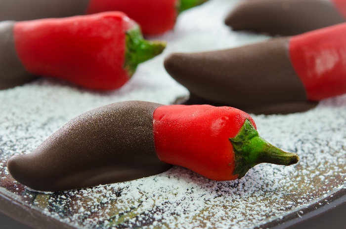 chilly peppers dipped in chocolate on a white sprinkled plate