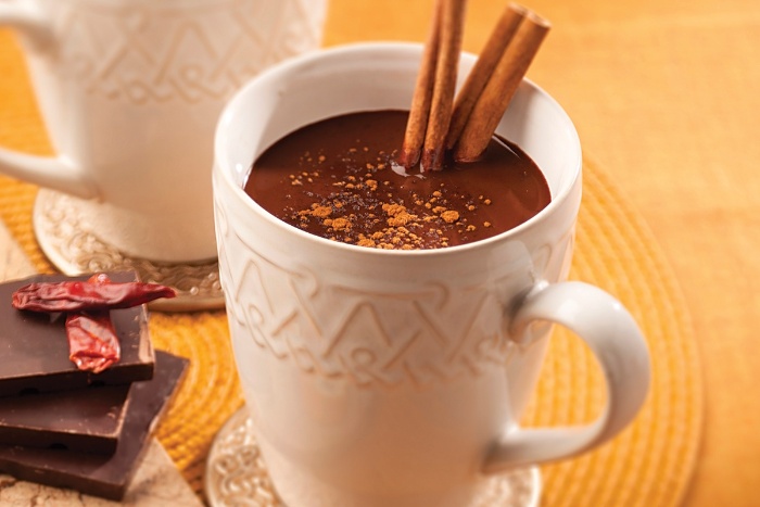 cinnamon and cocoa hot beverage in a white retro mug on a table with chocolate bars