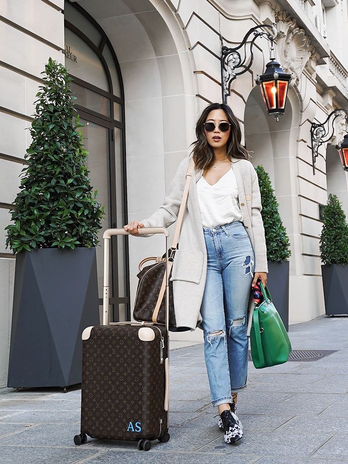 girl on a trip with her suitcases sunglasses and jeans on a street