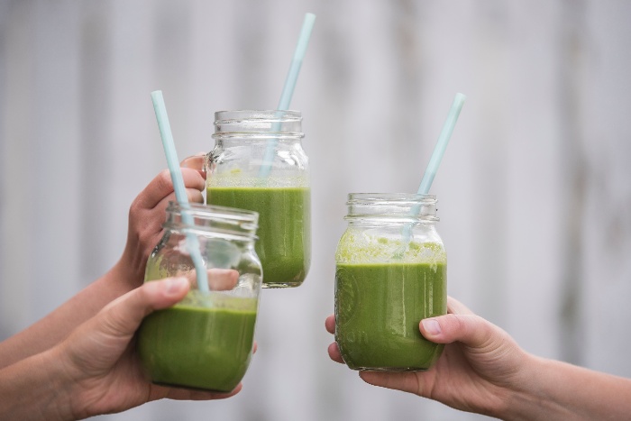 spring juicing challenge three hands cheering with jars of green juice with straws