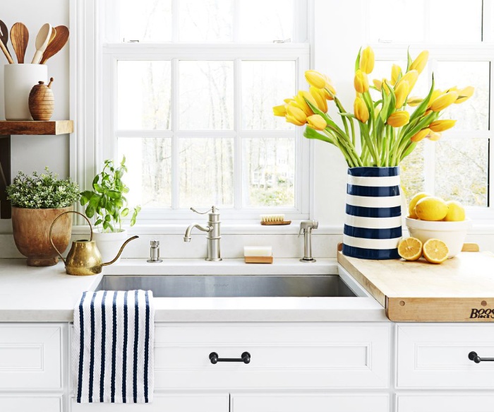 spring cleaning white kitchen sink with a vase with yellow tulips and lemons on the side