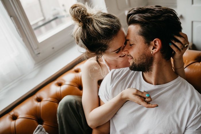 loving couple woman and man cuddling on a brown leather sofa